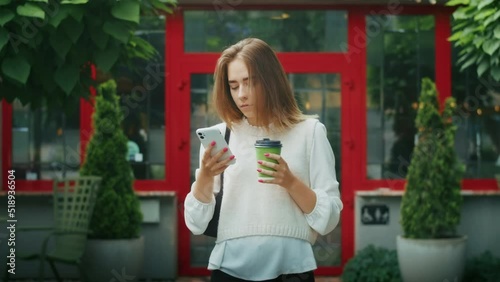 joyful girl drinks tea on the street in rainy weather, and speaks on the phone.