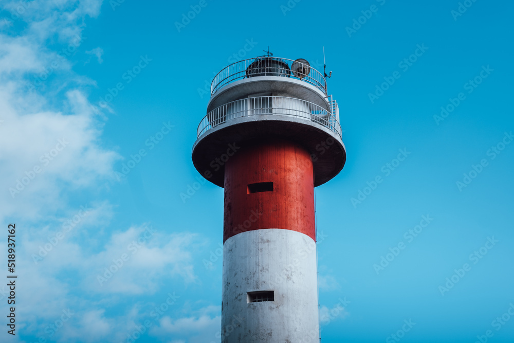 Detail of a white and red lighthouse on a sunny day with clouds Detail of a white and red lighthouse on a sunny day with clouds