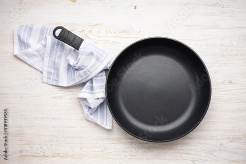 Fényképezés New frying pan and kitchen towel on a wooden background