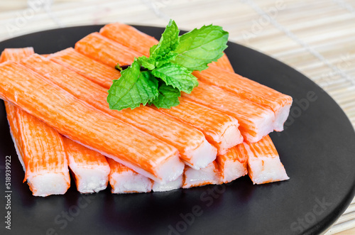 The Imitation Crab Stick in black dish with green leaf. photo