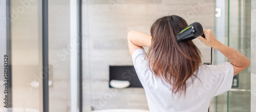 Foto young woman using hair dryer at home or hotel