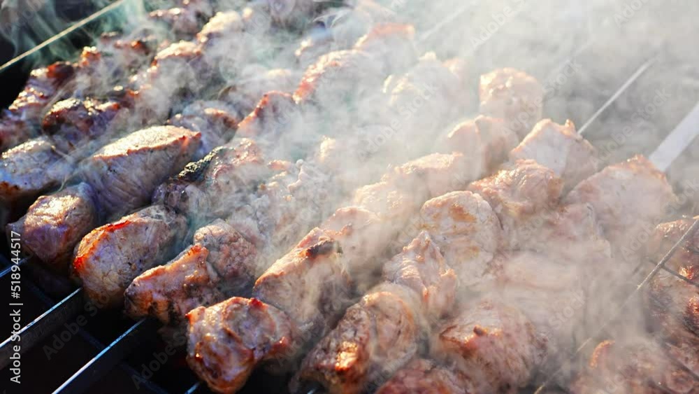Close-up of grilling tasty dish on barbecue. Process of cooking yummy shashlik in nature. Delicious food on metal skewer in bbq. Time to picnic concept. 