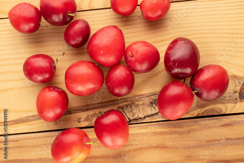 Several organic juicy cherry plums on a wooden table, close-up, top view.