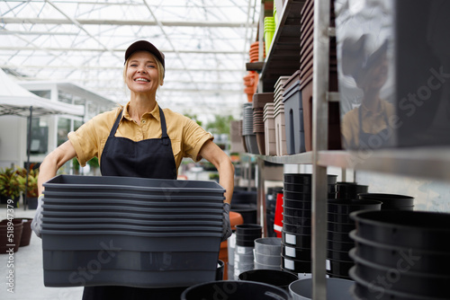Fotografi Portrait of a garden center worker with many flower pots in her hands