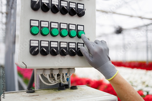 Foto Close-up of a flower greenhouse worker's hand in a glove pressing a button on th