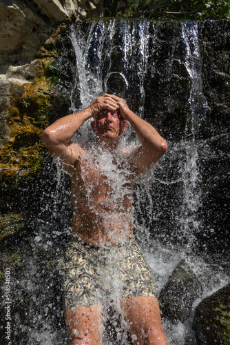 Permet  Albania A man sits under a waterfall at the Benja Thermal Baths in the mountains.