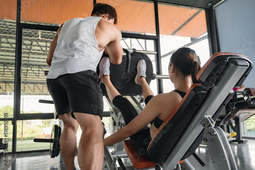 Young Asian male trainer is teaching Asian girls the right exercises in the gym. A young Asian bodybuilder trainer is teaching Asian women the correct use of exercise equipment in the gym.