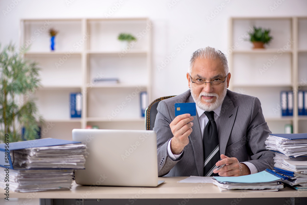 Old male employee holding credit card in the office Old male employee holding credit card in the office