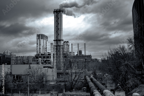 Combined heat and power plant. Smoke from the chimneys of a large factory. Large steam pipes of a working plant. The building of the old thermal power station under gloomy clouds photo