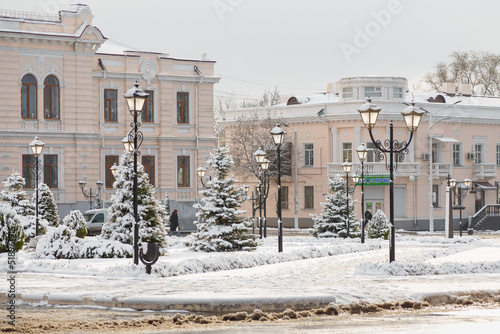 Beautiful winter cityscape: buildings, trees and street lamps covered with snow. Inscription on shop in Ukrainian - School child