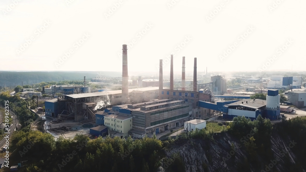 Air pollution by smoke coming out of five factory chimneys, industrial zone in the city, ecology concept. Stock footage. Aerial view of metallurgical production plant.