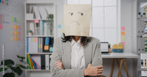 Fotografía Young Asian businesswoman sit on desk wear draw sad mask paper craft bag feel bad mood with fail work project at office