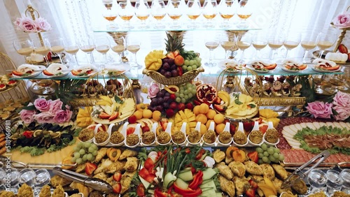 Beautiful buffet table at expensive banquet. Fresh organic fruits and vegetables, sweet desserts with crisps, mousse cakes and meringue rolls. Plates with cheese, meat and fish. Light alcoholic drinks