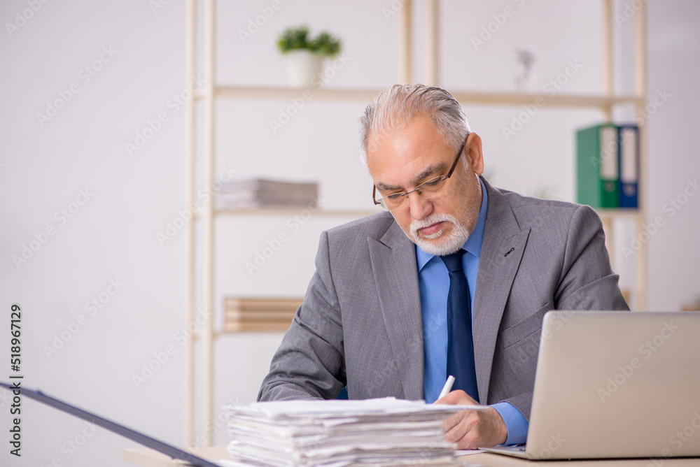 Fototapeta premium Old male employee working at workplace