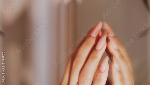 A girl's fragile hand with long nails. A woman gently runs her fingers over the mirror with a reflection. Self-perception and self-love. Care