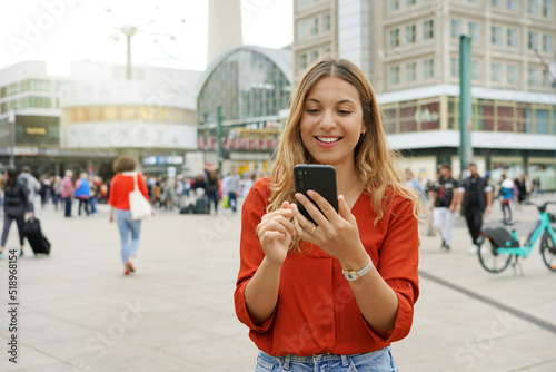 Photography Portrait of smiling young woman using a mobile app in Berlin city street, German