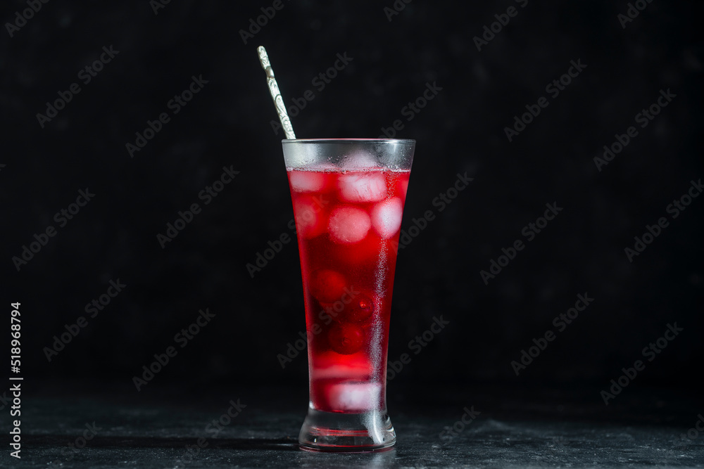 Fresh red cherry cocktail with ice cubes in glass on black background. Summer iced refreshing drink Fresh red cherry cocktail with ice cubes in glass on black background. Summer iced refreshing drink