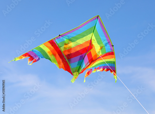colorful kite with many colors flying high in the blue sky