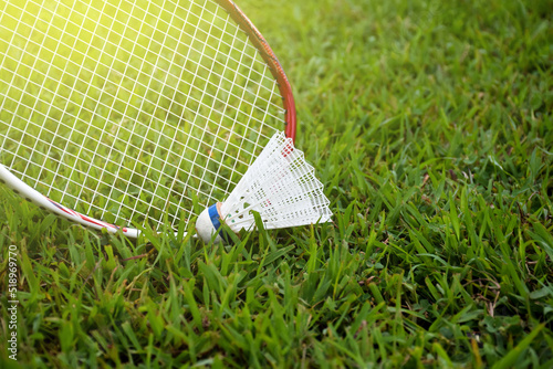 Picking up the badminton shuttlecock on grasslawn by using badminton racket, soft and selective focus on racket and shuttlecock, outdoor badminton playing concept. photo