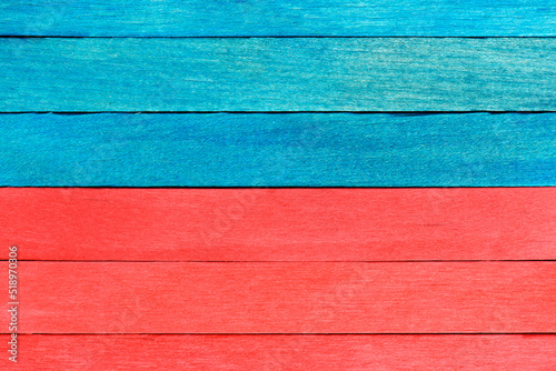 Bright bicolor background from red and blue wooden planks. Wooden textured background with natural patterns. Blue and red painted wooden boards arranged horizontally in a row.