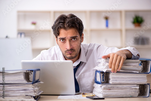 Young male employee and too much work in the office