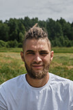 The concept of healthy lifestyle. Close up portrait of handsome Caucasian bearded man with dreadlocks. Athlete in white T-shirt in summer park. Male hipster.