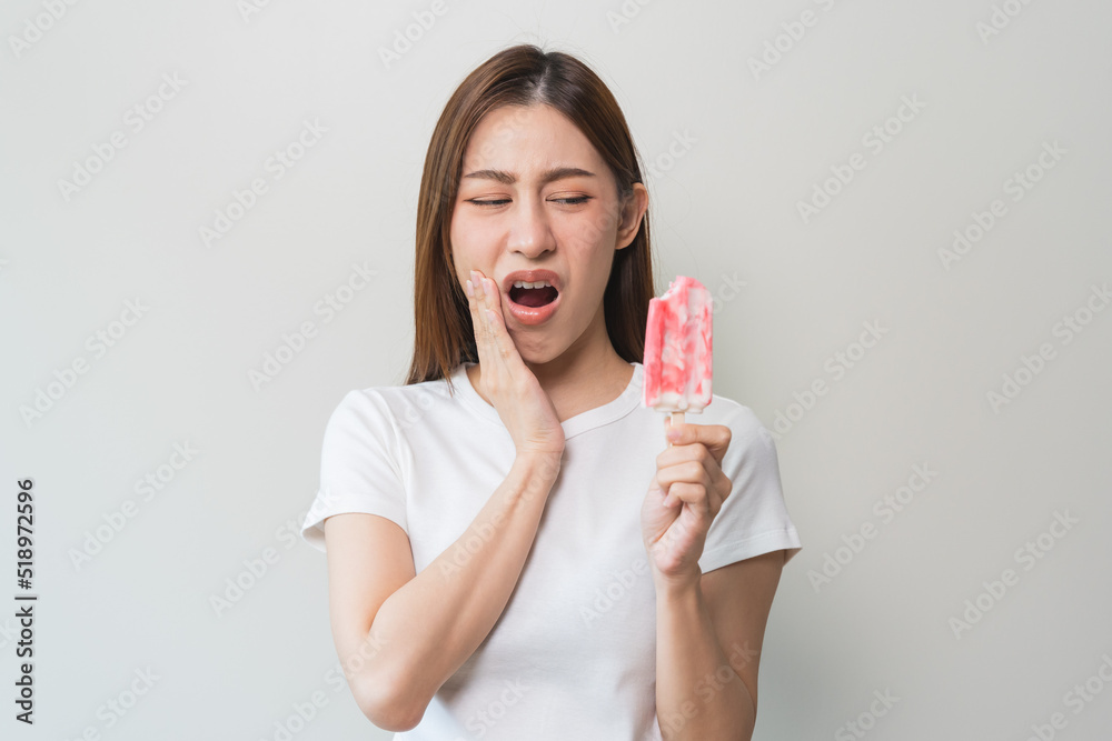 Face expression suffering from sensitive teeth, Asian young woman touching cheek Face expression suffering from sensitive teeth, Asian young woman touching cheek