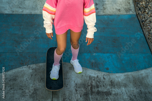 Little girl in bright clothes riding at the skateboard at the rollerdrome while enjoying photo