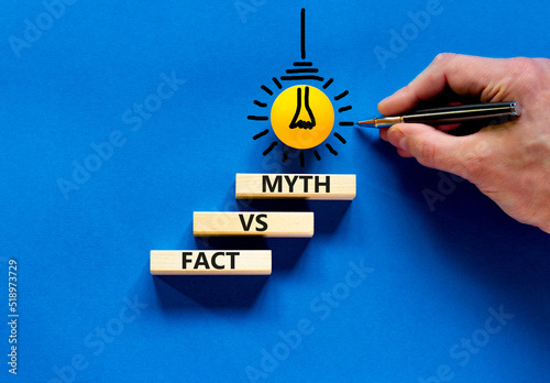 Fact vs myth symbol. Concept words Fact vs myth on wooden blocks on a beautiful blue table blue background. Businessman hand. Business, finacial and fact vs myth concept. Copy space.