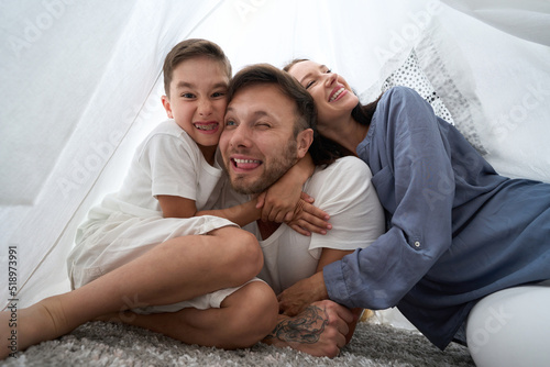 Caring parents play with their son in a shalash photo