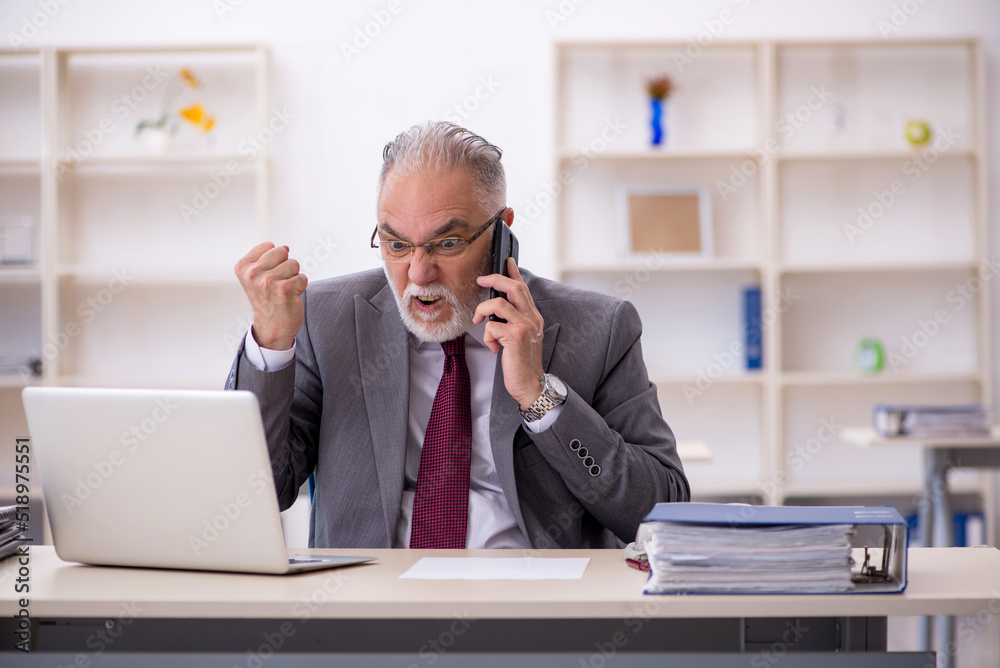 Old male employee working in the office Old male employee working in the office