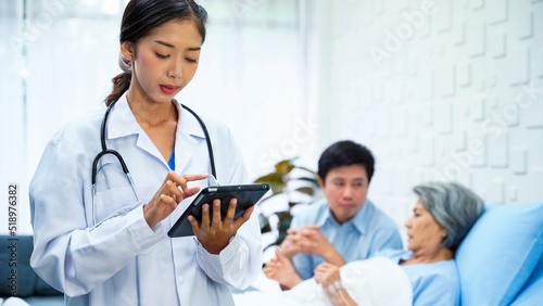 Female doctor is analyzing the symptoms of an elderly female patient. After examining the patient's body. Female doctor uses a tablet to record the results of a patient's treatment.