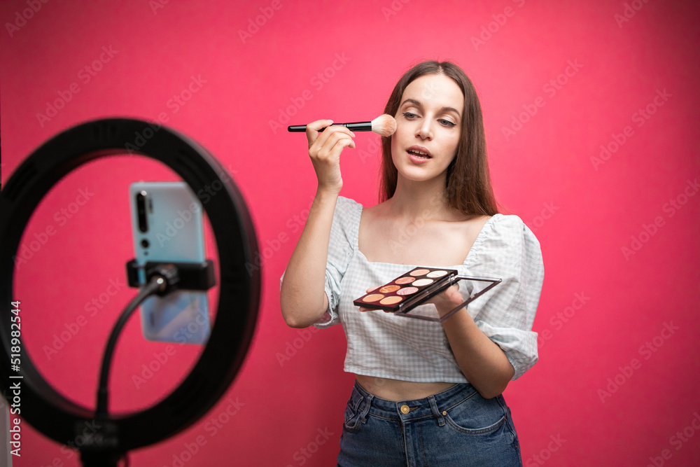 Beauty blogger recording makeup tutorial on pink background Beauty blogger recording makeup tutorial on pink background