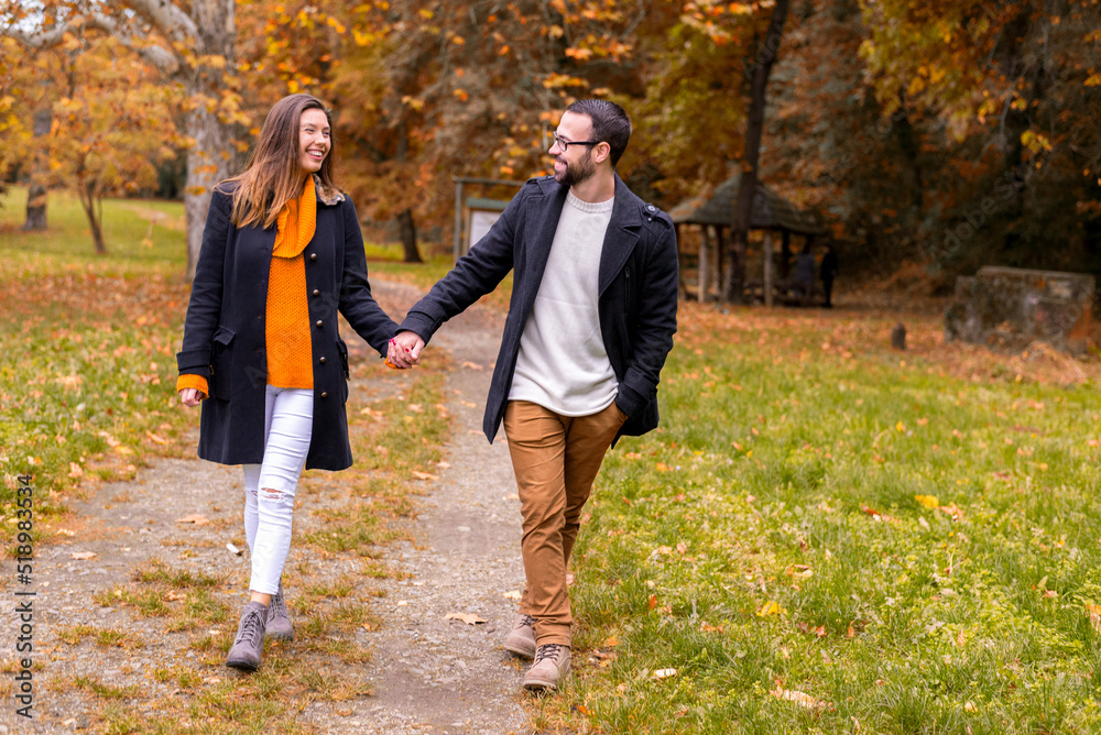 Fototapeta premium Smiling young couple in love having fun in the park on a beautiful autumn day