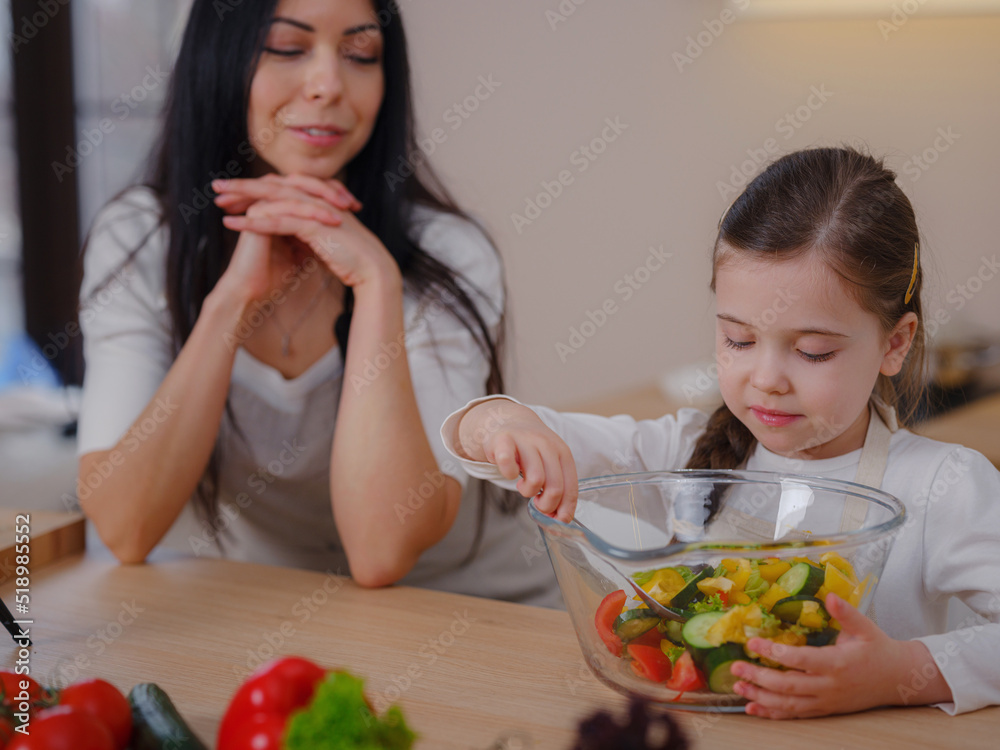 Happy mother and daughter enjoy prepare freshly salad together in kitchen. Healthy food at home. Healthy Lifestyle and Eating Concept. little influencer filming blog about healthy eating Happy mother and daughter enjoy prepare freshly salad together in kitchen. Healthy food at home. Healthy Lifestyle and Eating Concept. little influencer filming blog about healthy eating