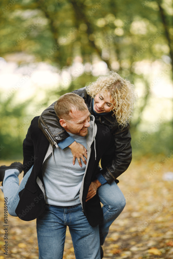 Man holding his girlfriend piggyback in a forest and posing for a photo