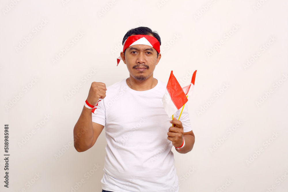 Asian man standing while clenching his hand and holding indonesian flag. Independence day concept