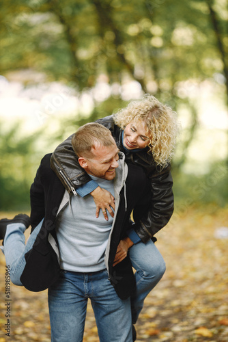 Man holding his girlfriend piggyback in a forest and posing for a photo