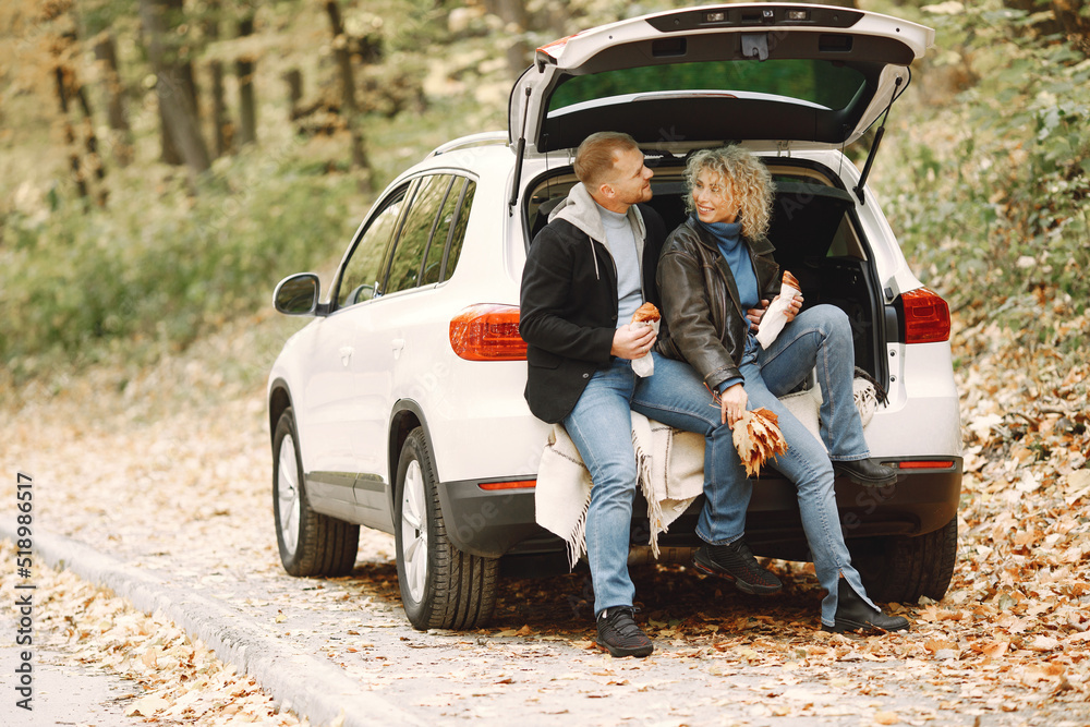 Romantic couple sitting in a trunk of white car in a forest and hugging Romantic couple sitting in a trunk of white car in a forest and hugging