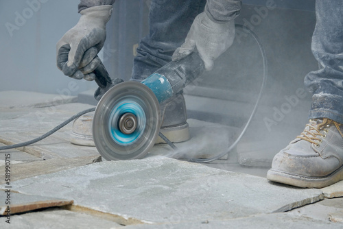 closeup of worker using electric saw to trim flagstone