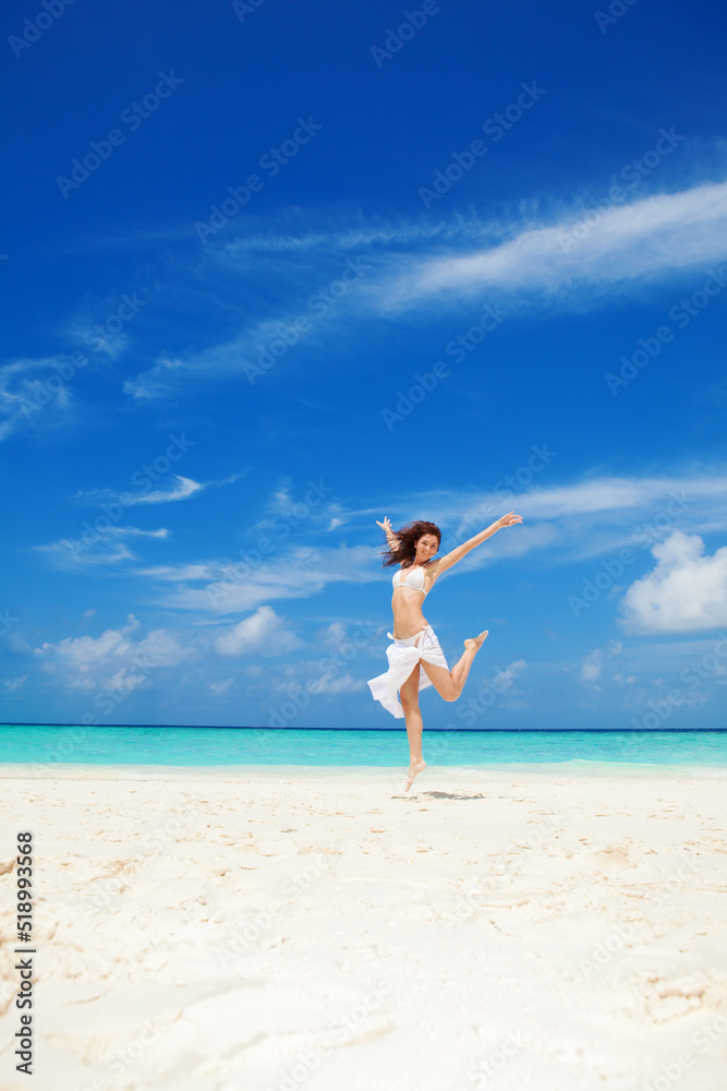 Happy young woman jumping on the beach. White sand, blue cloudy sky and crystal sea of tropical beach. Vacation. Ocean beach relax, travel to islands. Happy lifestyle. Happy young woman jumping on the beach. White sand, blue cloudy sky and crystal sea of tropical beach. Vacation. Ocean beach relax, travel to islands. Happy lifestyle.