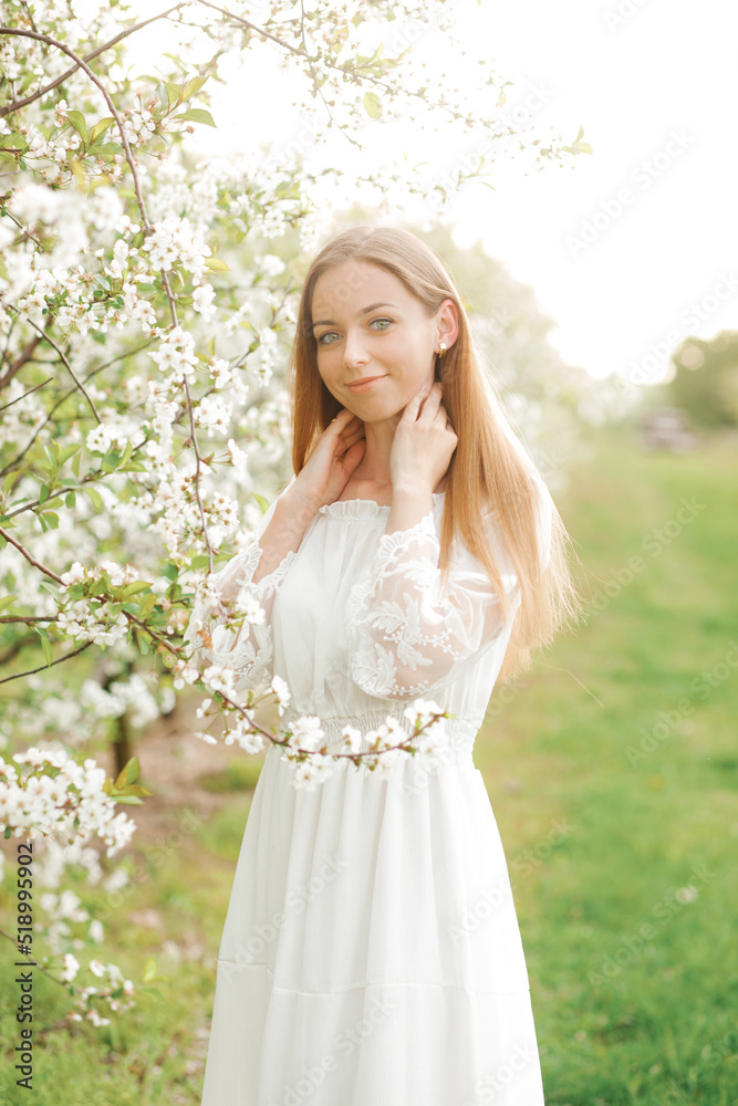 Amazing young woman posing in a garden of flowering trees in spring.