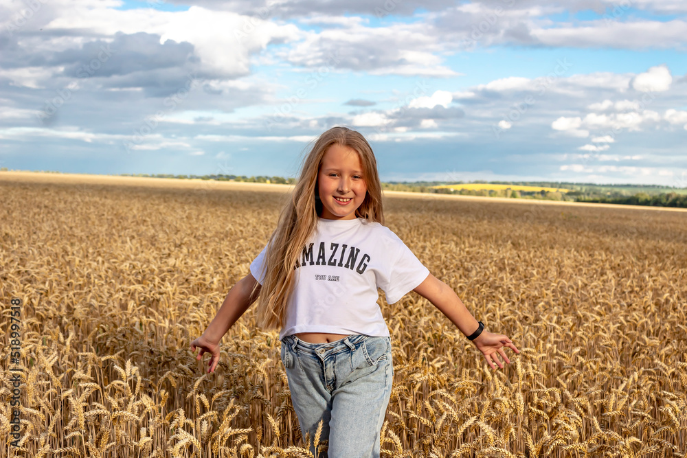 Happy girl with long hair in a wheat field. Sunset. The girl is wearing blue jeans and a white t-shirt. Happy girl with long hair in a wheat field. Sunset. The girl is wearing blue jeans and a white t-shirt.