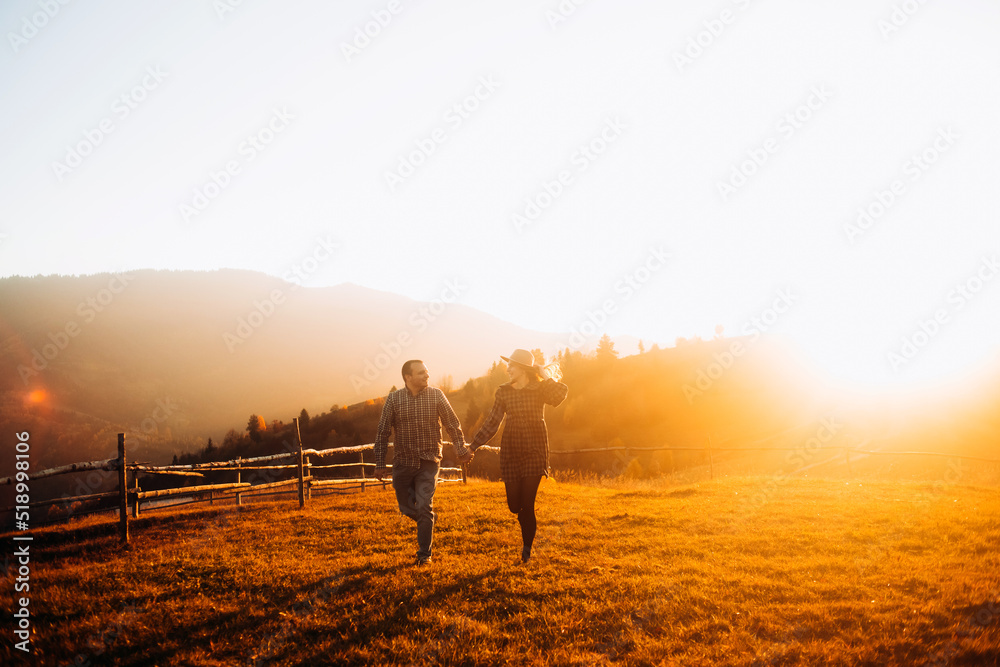 Crazy couple running, holding hands, enjoying each other at sunset. Leisure in the mountains.