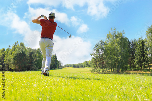 Full length of golf player playing golf on sunny day. Professional male golfer taking shot on golf course.