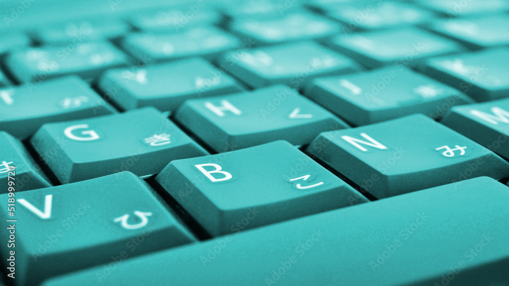 Japanese typing. Turquoise laptop keyboard closeup. Symbols on buttons of hiragana. Light teal tinted computer wallpaper or background. Electronic commerce in Japan. IT technology and data storage Japanese typing. Turquoise laptop keyboard closeup. Symbols on buttons of hiragana. Light teal tinted computer wallpaper or background. Electronic commerce in Japan. IT technology and data storage