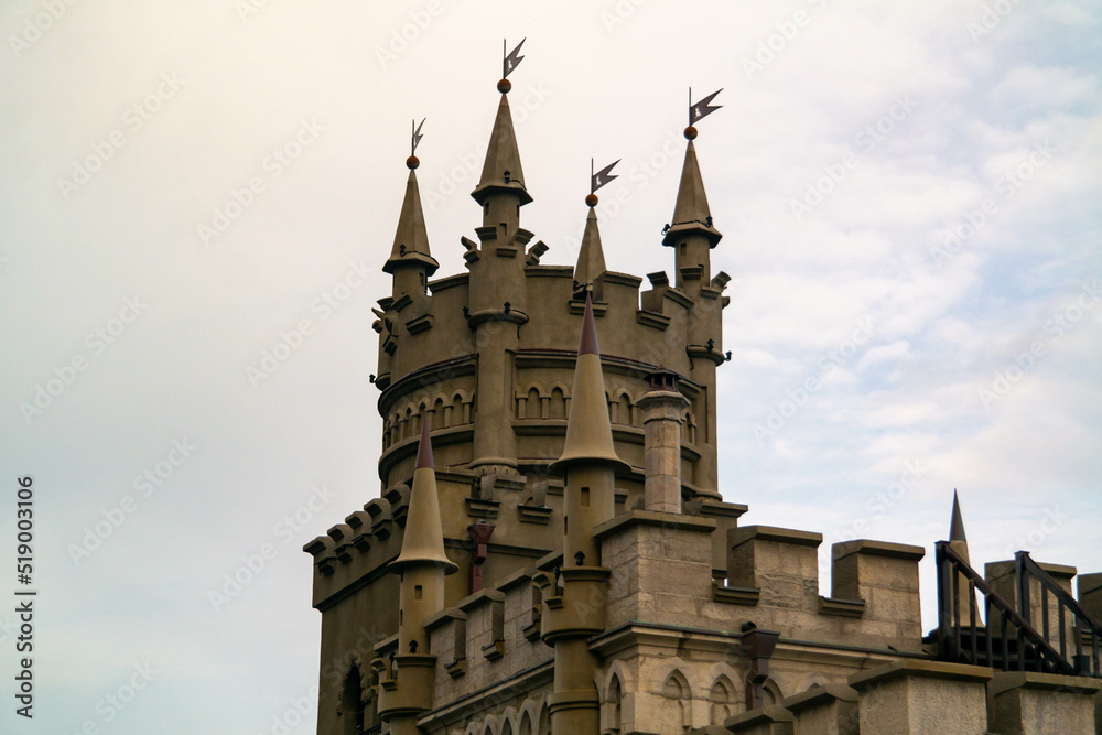 The top of a Gothic castle in close-up against a cloudy sky and