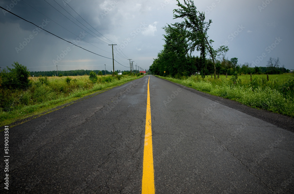 Country Road with Yellow Line During a Summer Storm Country Road with Yellow Line During a Summer Storm