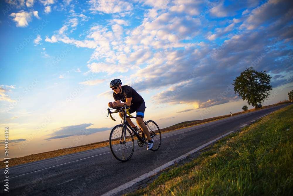 Fototapeta premium Young sports man cycling with bicycle on the road in summer