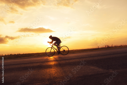 Young sports man cycling with bicycle on the road in summer